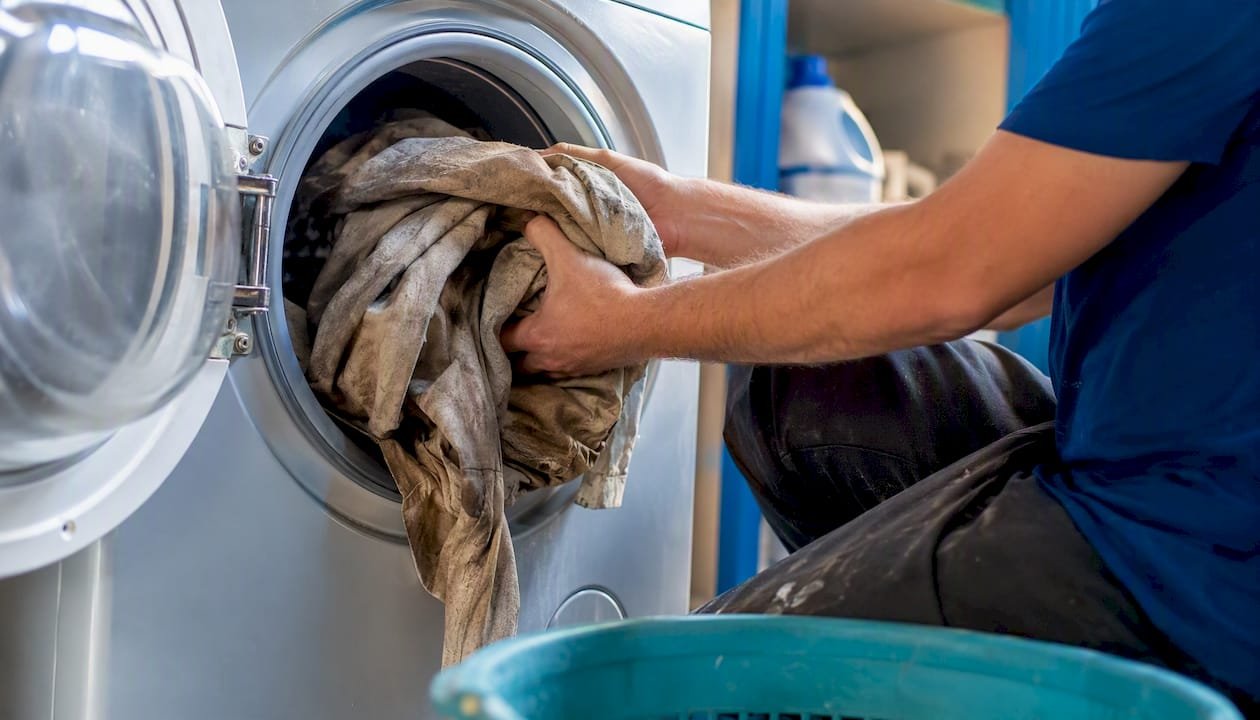 Hands loading work clothes into front-load washer