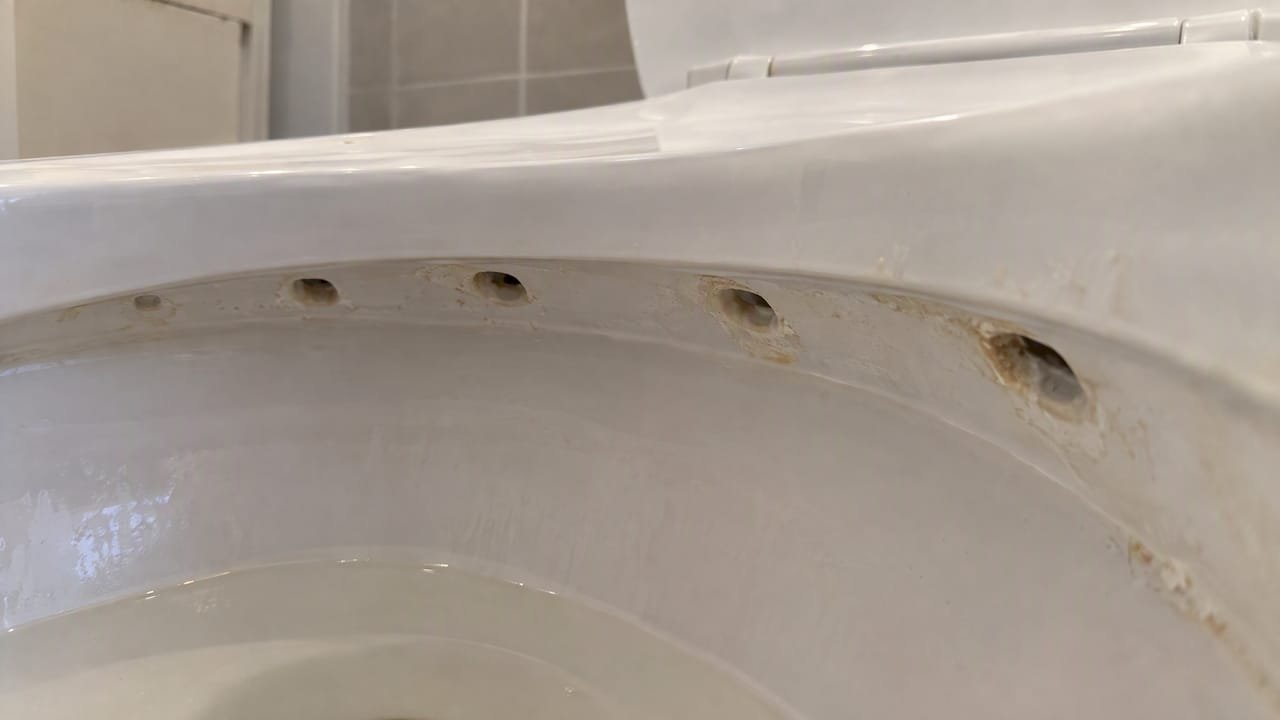 Mineral deposits around toilet bowl rim jets